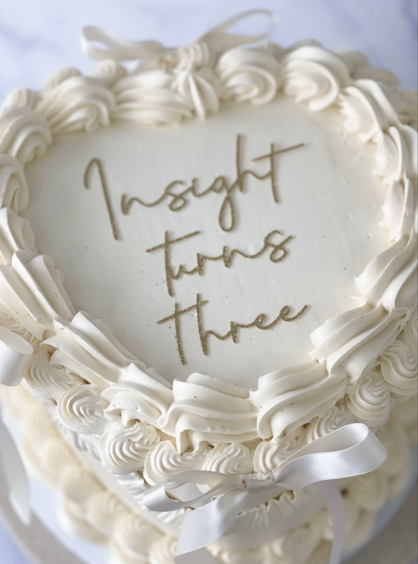 Hands piping buttercream rosettes onto a soft pink cake