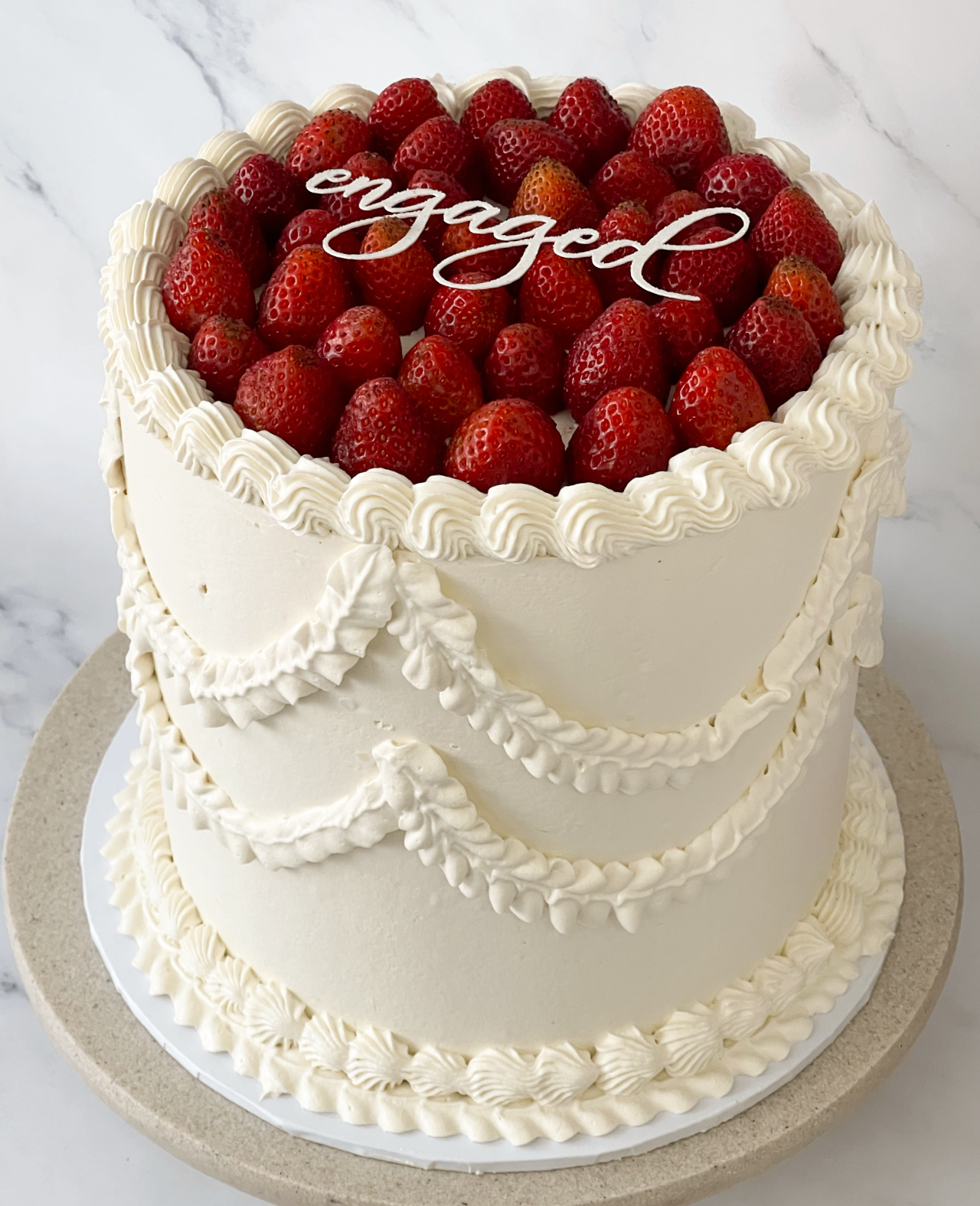 Three-tier ivory buttercream celebration cake with dusty rose peonies