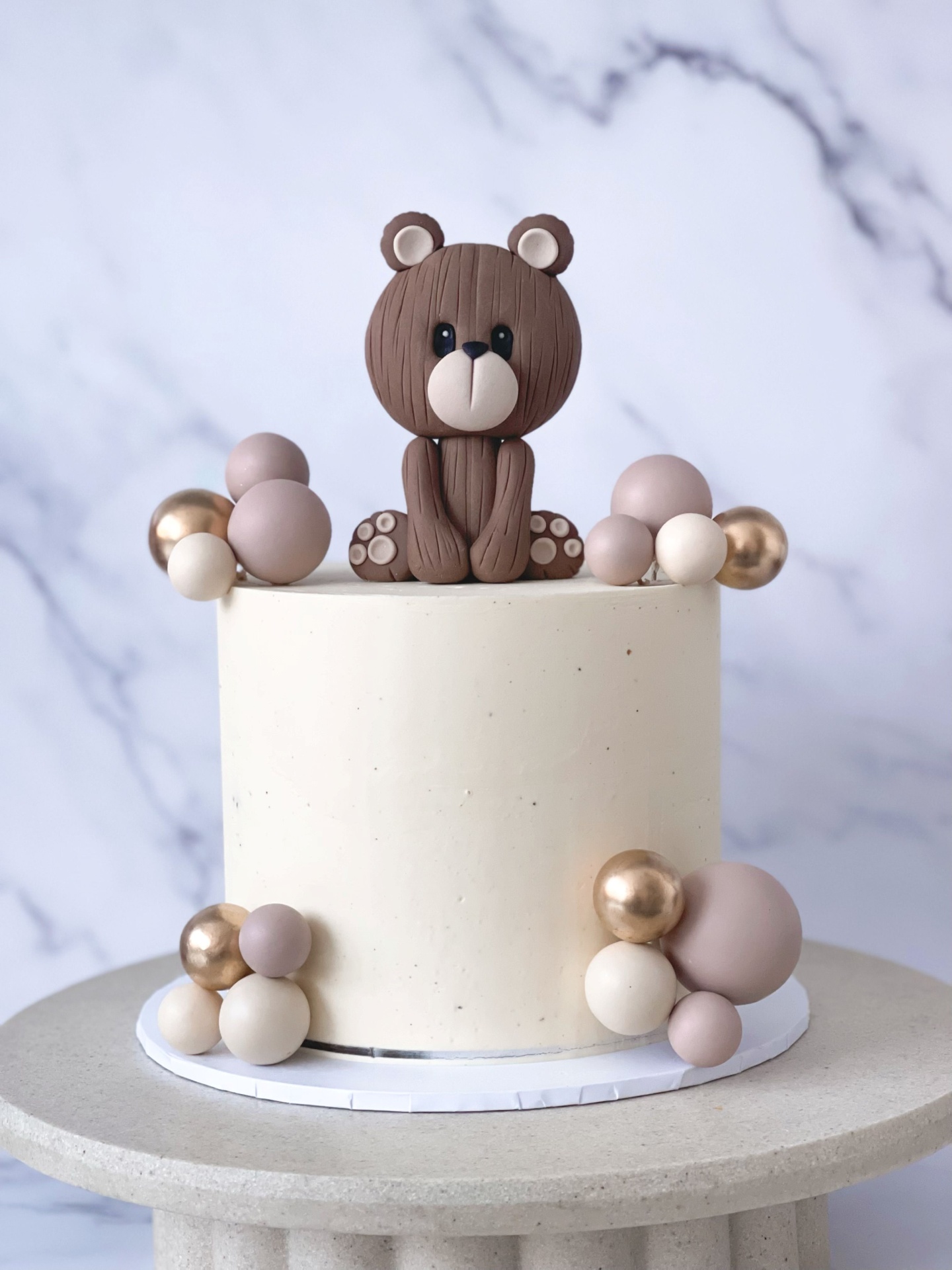 Cream buttercream cake with fondant teddy bear topper and blush sphere garland