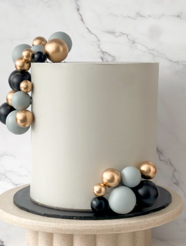 Ivory celebration cake with gold, navy and dusty blue sphere arrangement